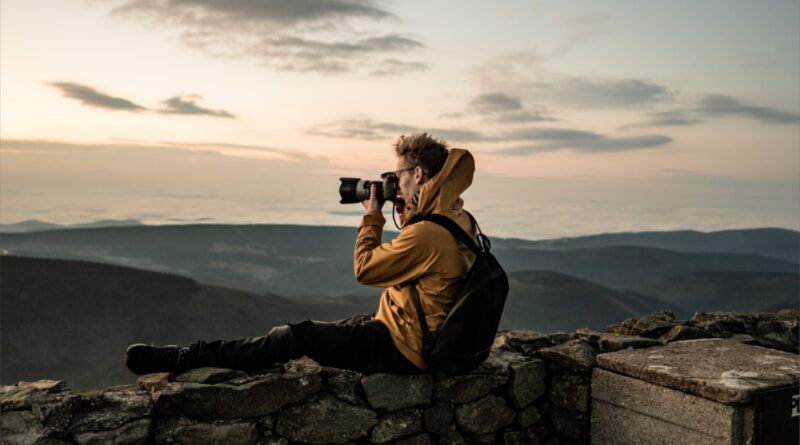 man in brown jacket taking photo of mountain during daytime