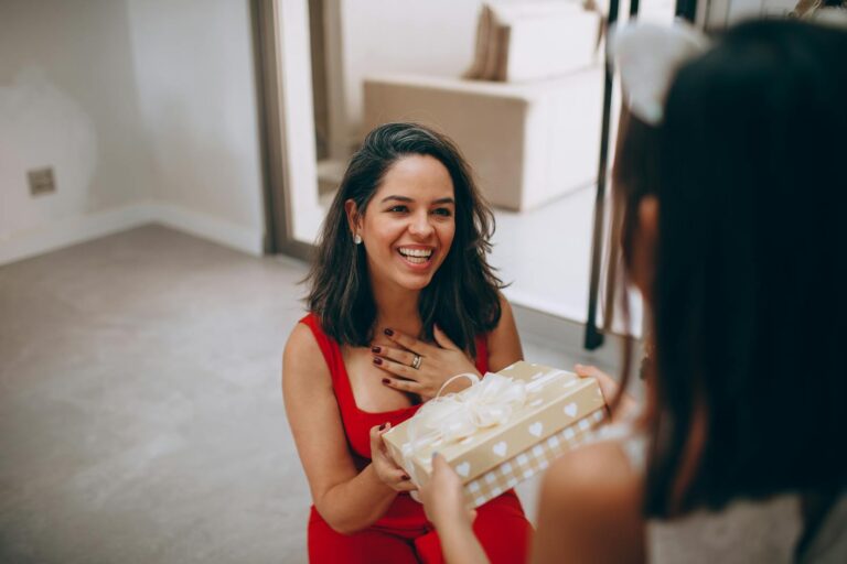 A happy woman receives a gift from her daughter indoors, capturing a moment of joy and connection.