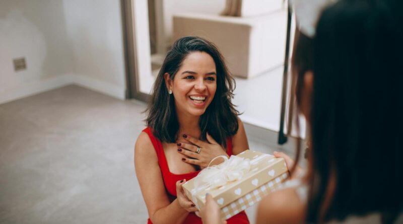 A happy woman receives a gift from her daughter indoors, capturing a moment of joy and connection.