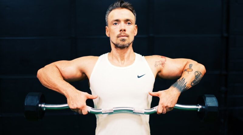 man in white tank top holding gray metal bar