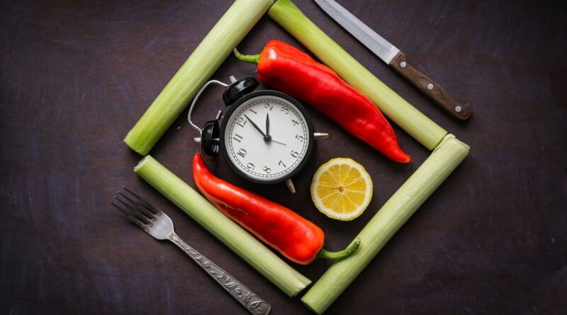 a clock surrounded by vegetables and a knife